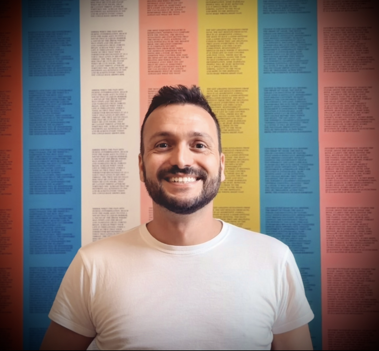 Foto de Gio sonriendo frente a un mural colorido